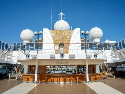 Detailansicht der Lo Spinnaker Bar auf einem Oberdeck der MSC Opera, umgeben von Stufen, Relingen und großen weißen Kuppeln unter blauem Himmel.