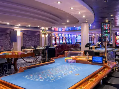 Eine Innenansicht des eleganten "Med Pearl" Casinos an Bord der MSC Opera, mit mehreren Roulette-Tischen, glänzenden Spielautomaten und farbenfrohen Jetons.