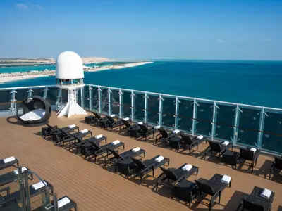 Das Sonnendeck der MSC Opera mit Liegestühlen, Handtüchern, Radarkuppel und weitem Blick auf das blaue Meer und eine Küstenlandschaft.