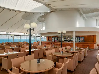 Die Il Patio Bar und Lounge an Bord der MSC Opera bietet eine entspannte Atmosphäre mit zahlreichen Sitzgelegenheiten, einem Bar-Tresen und einem weiten Blick auf das offene Meer unter einer eleganten Zeltdachkonstruktion.