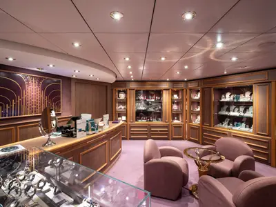Elegante La Gioielleria an Bord der MSC Opera. Vitrinen voller Schmuck und Uhren. Verkaufstresen, bequeme Sessel und ein Kunstwerk. Einladendes Ambiente.