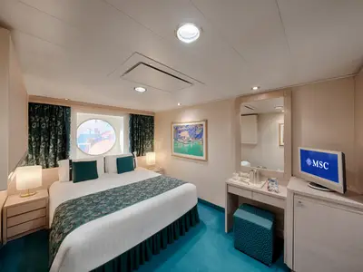 Blick in eine helle, modern eingerichtete Aussenkabine der MSC Orchestra. Das Doppelbett ist mit blau-gruenen Akzenten dekoriert. Ein Porthole bietet Tageslicht, daneben ein Schreibtisch mit Spiegel und TV.