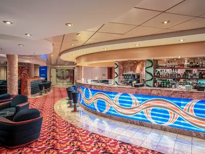 Elegante L'Incontro Bar an Bord der MSC Orchestra. Geschwungene Bar mit leuchtender blauer Front, Spirituosenregalen und Kaffeemaschine. Bequeme Lounge-Sessel auf rotem Teppich. Warme Atmosphäre.