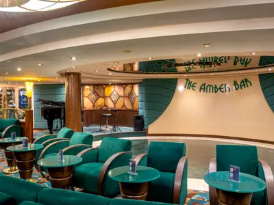 Die Amber Bar an Bord der MSC Orchestra. Elegante Lounge mit grünen Samtsesseln, Tischen, Bühne mit Flügel. Verspiegelte Decke und kunstvolle Wandpaneele.