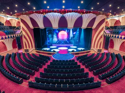 Das opulente Covent Garden Theatre an Bord der MSC Orchestra, mit rotem Teppich, blauen Sitzen und einer modern beleuchteten Bühne.