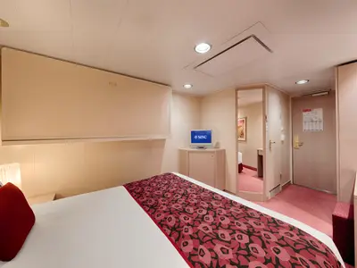 Eine helle und gemuetliche Innenkabine an Bord der MSC Orchestra. Sie verfuegt ueber ein Doppelbett mit roter Tagesdecke, einen Fernseher und eine Spiegeltuer.
