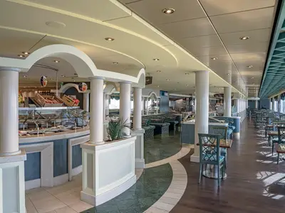 Weitwinkelaufnahme des Buffetrestaurants Four Seasons an Bord der MSC Orchestra. Rechts viele leere Tische und Stühle, links eine Salatbar mit Speisen.