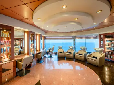Ein luxuriöser Friseursalon an Bord der MSC Orchestra, ausgestattet mit modernen Frisierplätzen und Haarwaschbeckenstühlen, die einen weiten Blick auf das offene Meer bieten.