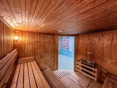 Saunakabine an Bord der MSC Orchestra mit Holzbänken und warmem Licht. Ein Durchgang führt zu einem gefliesten Wellnessbereich mit Mosaik.