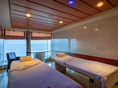 Zwei Massageliegen mit weißen Handtüchern und weitem Meerblick durch große Fenster im MSC Aurea Spa der MSC Orchestra. Der Raum ist hell und einladend gestaltet.