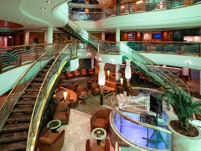 Atrium der MSC Poesia: Geschwungene Treppen, stilvolle Lounge-Bereiche auf mehreren Ebenen und ein transparenter Flügel prägen das elegante Ambiente.