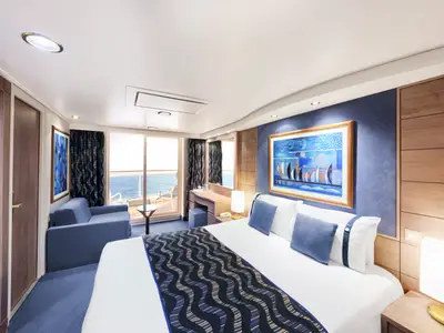 Moderne Balkonkabine an Bord der MSC Poesia mit Doppelbett, blauem Sofa und Meerblick vom privaten Balkon. Helles, einladendes Ambiente mit Kunst an der Wand.