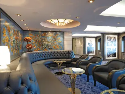 Eine luxuriöse Bar-Lounge an Bord der MSC Poesia mit einem langen, blauen Chesterfield-Sofa, passenden Sesseln, goldenen Beistelltischen und einer kunstvollen Wandmalerei mit Weinranken und Trauben.