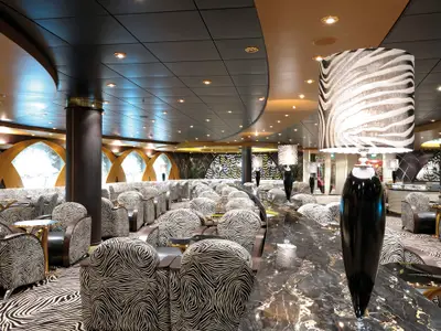 Die stilvolle Zebra Bar an Bord der MSC Poesia zeigt zahlreiche Sessel und Sofas mit schwarz-weiss gestreiftem Bezug. Schwarze Marmortische und Stehlampen ergänzen das Design unter einer modernen Decke.