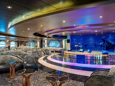 Die Zebra Bar an Bord der MSC Poesia. Rechts Bühne mit Instrumenten, links Sitzbereiche im Zebra-Muster, reflektierende Tanzfläche, bunte Beleuchtung.