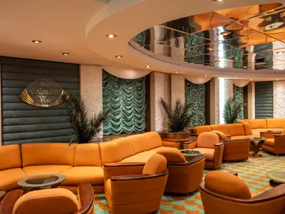 Einladende Le Rendez Vous Bar an Bord der MSC Poesia mit orangefarbenen Sitzgruppen, tiefen Sofas und Sesseln um Glastische. Eine Spiegeldecke und dekorative Elemente schmücken den Raum.