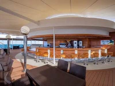 Die leere Mojito Bar an Bord der MSC Poesia, ein stilvoller Holz-Barbereich auf dem Oberdeck mit Blick auf das Meer. Umgeben von Tischen und Stühlen unter einem schützenden Segeldach.