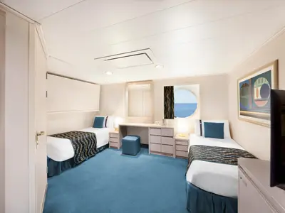 Geräumige Aussenkabine an Bord der MSC Poesia, rollstuhlgerecht, mit zwei Einzelbetten, Schreibtisch, TV und rundem Fenster mit Meerblick. Blauer Teppichboden.