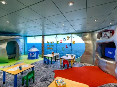 Ein farbenfroher Spielbereich "I Dinosauri Mini Club" an Bord der MSC Poesia mit Basteltischen, Spielzelten und Höhlen. Große Fenster bieten einen weiten Blick auf das blaue Meer.