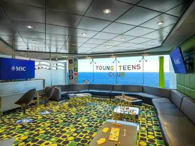 Ein lebhafter Young Teens Club an Bord der MSC Poesia mit moderner Einrichtung, Sofas, Spielen und großen Fenstern mit Meerblick.