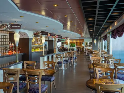 Ansicht des hellen und geräumigen Buffet-Restaurants mit zahlreichen Tischen und Stühlen und weitem Meerblick durch Panoramafenster an Bord der MSC Poesia.