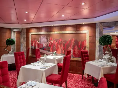 Elegantes Restaurant Il Palladio, MSC Poesia. Rote Stühle und Teppich. Wandmalerei zeigt Villa und rote Bäume. Weiss gedeckte Tische bereit für Gäste.