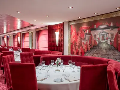Das elegante Restaurant Il Palladio an Bord der MSC Poesia: Rote Samtsessel, gedeckte Tische und ein Wandgemälde mit Herrenhaus.