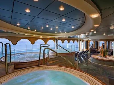 Der helle Thermalbereich des MSC Aurea Spa an Bord der MSC Poesia mit mehreren Sprudelbecken, luxuriösen Liegen und großartigen Panoramafenstern zum Meer.