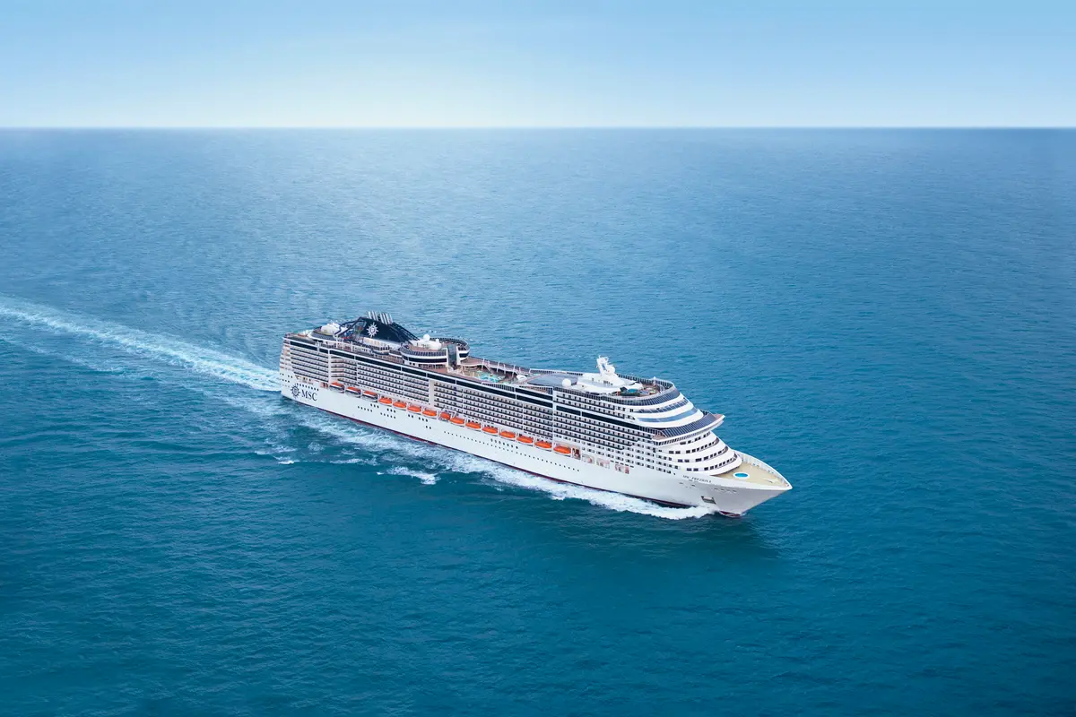 Eine atemberaubende Luftaufnahme der MSC Preziosa, die majestätisch auf blauem Meer fährt. Die Bugwelle ist deutlich sichtbar und das Schiff hinterlässt eine weisse Spur im Wasser.