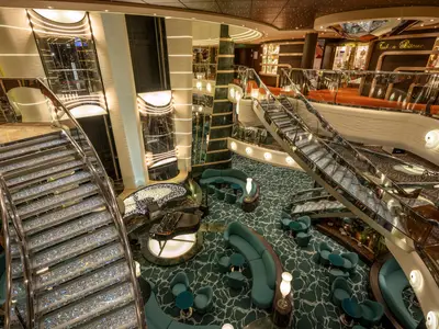 Das elegante Atrium an Bord der MSC Preziosa. Glitzernde Treppen, eine Pianobar und luxuriöse Lounge-Bereiche. Warme Lichtinstallationen schaffen ein gehobenes Ambiente.