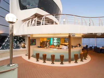 Die Turquoise Bar an Bord der MSC Preziosa. Eine helle, moderne Bar auf dem Deck mit Meerblick, umgeben von eleganten Sitzgelegenheiten und einer gut bestückten Theke. Hohe Barhocker und ein glänzender Boden.