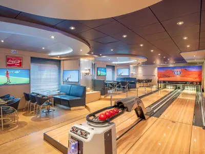 Die moderne Sports Bar & Bowling an Bord der MSC Preziosa zeigt eine Doppel-Bowlingbahn und mehrere Fernseher mit Tennisübertragungen. Bequeme Sitzbereiche mit Tischen laden zum Verweilen ein.