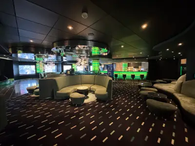 Innenansicht der stilvollen Lounge-Bar an Bord der MSC Preziosa mit geschwungenen gruenen Sofas und glaenzenden Lichtdecken.