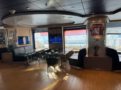 Blick in die Sports Bar an Bord der MSC Preziosa mit gemütlichen Sitzecken, Bildschirmen und Fußball-Trikots in Vitrinen.