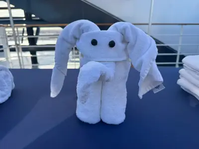 Eine kunstvoll gefaltete Handtuchfigur in Form eines Elefanten auf einem Tisch an Deck der MSC Preziosa.
