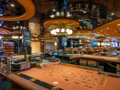 Das elegant beleuchtete Millennium Star Casino an Bord der MSC Preziosa mit mehreren Roulette-Tischen, glänzenden Spielautomaten und einer Bar im Hintergrund. Das Design ist luxuriös mit goldenen Akzenten und einer reflektierenden Decke.