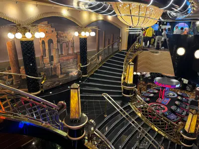 Blick auf den prunkvollen Treppenbereich mit Wandgemälden und goldenen Geländern neben dem Casino an Bord der MSC Preziosa.