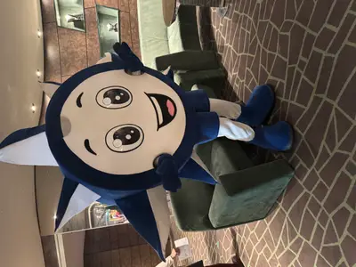 Das blaue, sternförmige MSC-Maskottchen Doremi posiert lächelnd in einem Salon an Bord der MSC Preziosa.