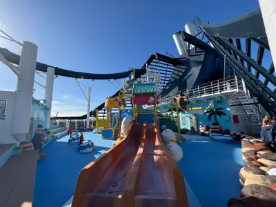 Der bunte Kinder-Wasserpark Doremi Castle an Bord der MSC Preziosa mit einer Rutsche unter blauem Himmel.