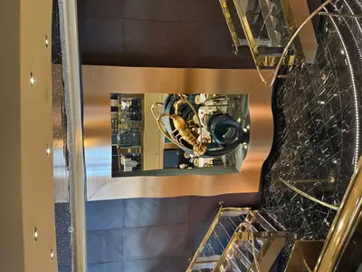 Nahaufnahme einer kunstvollen, goldenen Hummerskulptur in einem Rahmen an Bord der MSC Preziosa, umgeben von edlem Marmorboden und Goldgeländern.