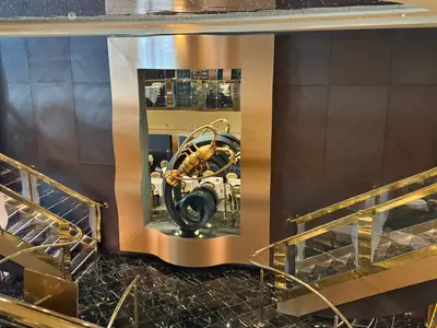 Eine goldene Hummerskulptur in einem goldenen Rahmen, umgeben von eleganten Treppen an Bord der MSC Preziosa.