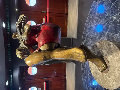 Eine moderne Bronzeskulptur einer Gitarrenspielerin in rotem Kleid an Bord der MSC Preziosa.