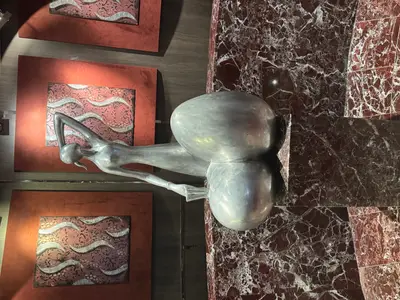 Eine moderne, silberfarbene Skulptur einer weiblichen Figur auf einem Marmorsockel an Bord der MSC Preziosa.