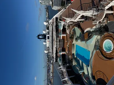 Ein Foto von oben auf das Außendeck mit Pool und Whirlpools an Bord der MSC Preziosa bei klarem Himmel.