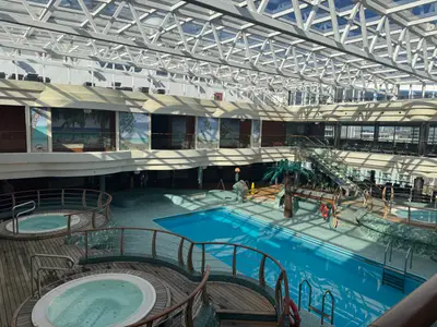 Der lichtdurchflutete, überdachte Poolbereich mit Whirlpools und Liegen an Bord der MSC Preziosa.