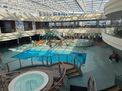 Einladender überdachter Poolbereich mit blauem Schwimmbecken und Whirlpools an Bord der MSC Preziosa.