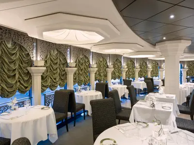 Elegantes Restaurant an Bord der MSC Preziosa mit gedeckten Tischen, Vorhängen und dekorativen Gittern an den Fenstern.