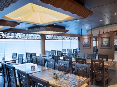 Innenansicht des Inca & Maya Buffetrestaurants der MSC Preziosa. Zahlreiche Tische und Stühle mit dekorativen Mustern. Große Fensterfront bietet Panoramablick auf das weite Meer.
