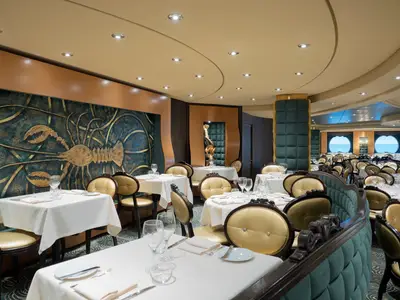 Das elegante Restaurant 'The Golden Lobster' der MSC Preziosa. Gedeckte Tische, goldene Stühle, eine goldene Hummer-Wandkunst und Meerblick durch Bullaugen.
