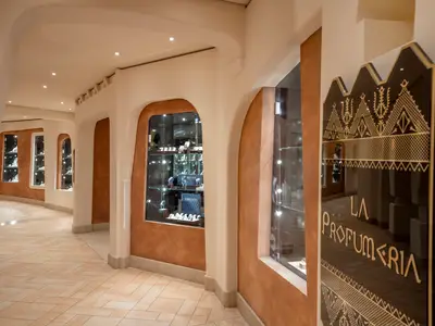 Innenansicht einer eleganten Ladenzeile mit Schaufenstern für Uhren, Schmuck und einer Parfumerie, an Bord der MSC Preziosa.